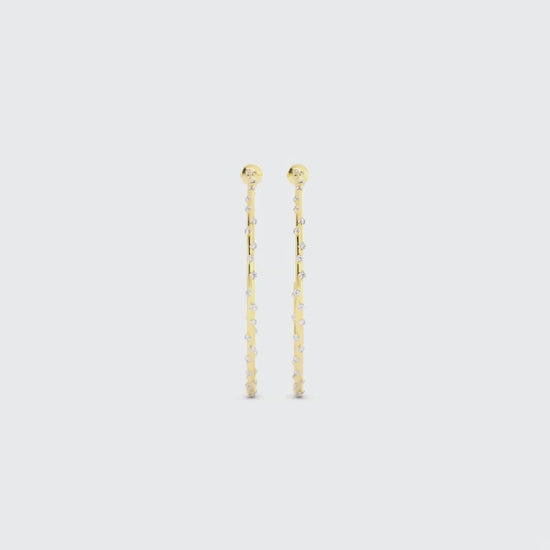 Video of long gold drop earrings with small embedded gemstones on a white background